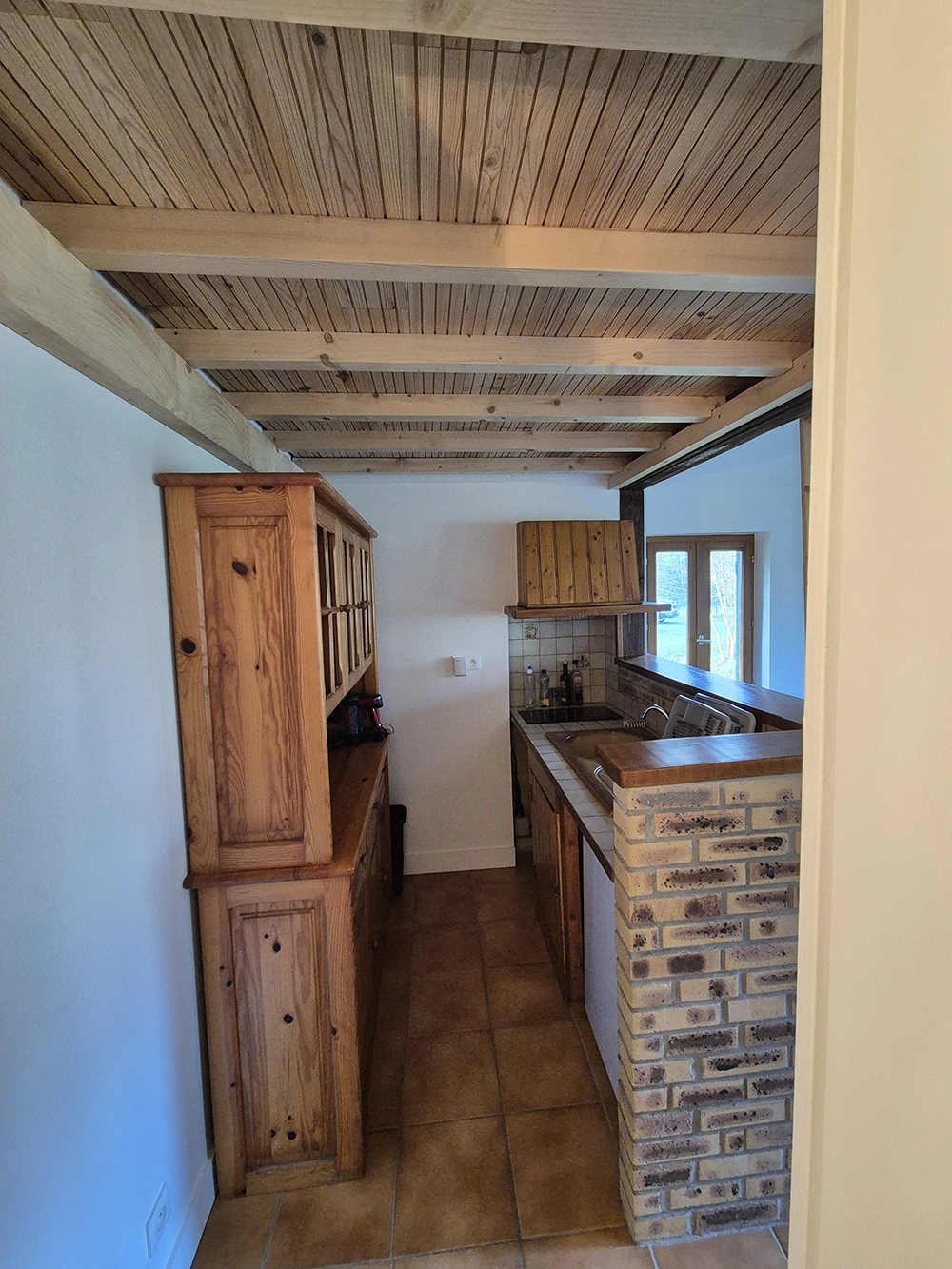 Wider kitchen view with a cupboard on the left and kitchen counter on the right.